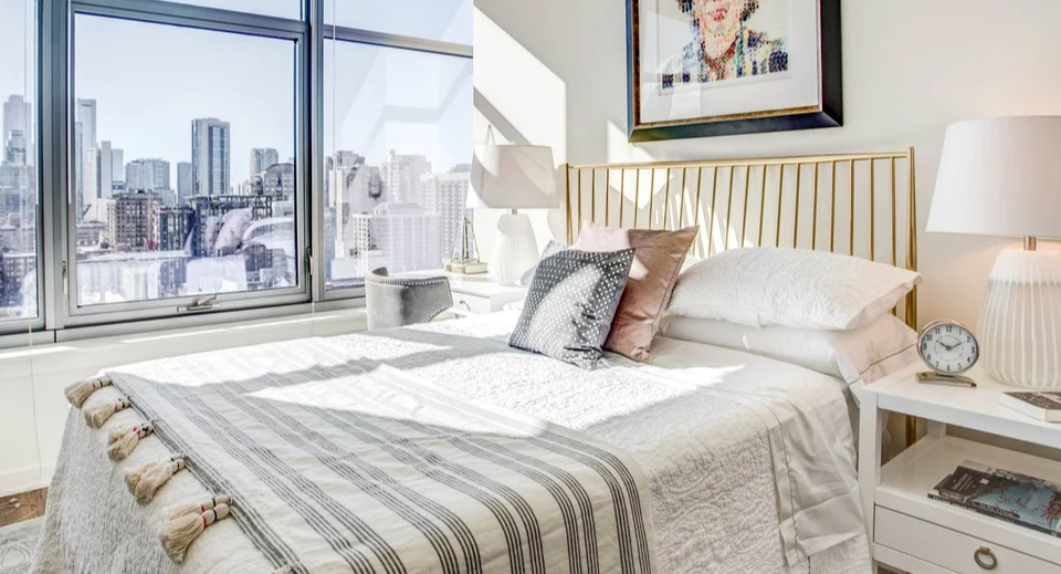 Stylish bedroom featuring a comfortable bed, contemporary art, and large windows with urban views at NEXT Apartments Chicago