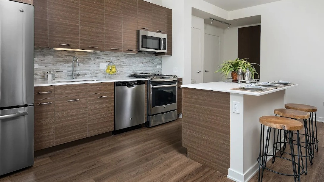 Stylish kitchen featuring dark wood cabinetry, stainless steel appliances, and a convenient island with bar seating at NEXT Apartments in Chicago