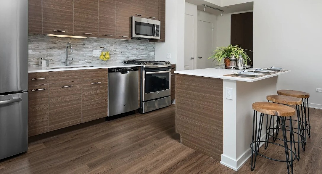 Stylish kitchen featuring dark wood cabinetry, stainless steel appliances, and a convenient island with bar seating at NEXT Apartments in Chicago