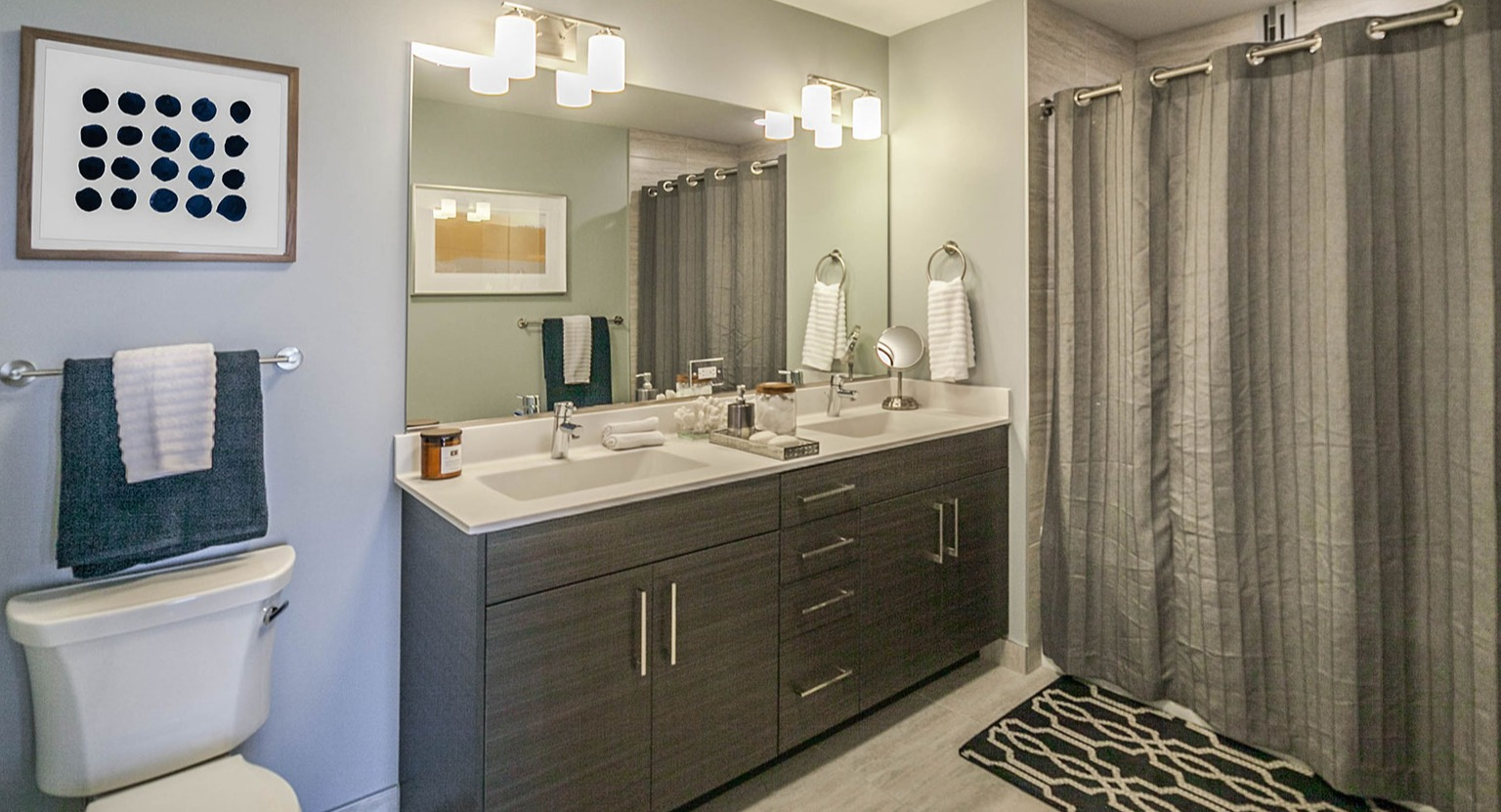 Modern apartment bathroom at Niche 905 in Chicago, featuring a double vanity, toilet, and a large walk-in shower with sleek tiles