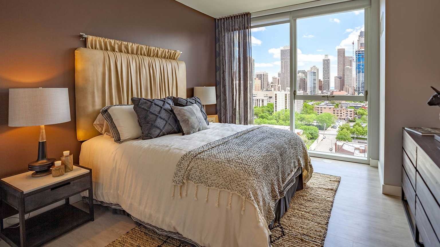 Luxurious bedroom at Niche 905 in Chicago, featuring a large bed, elegant decor, and stunning city views from floor-to-ceiling windows