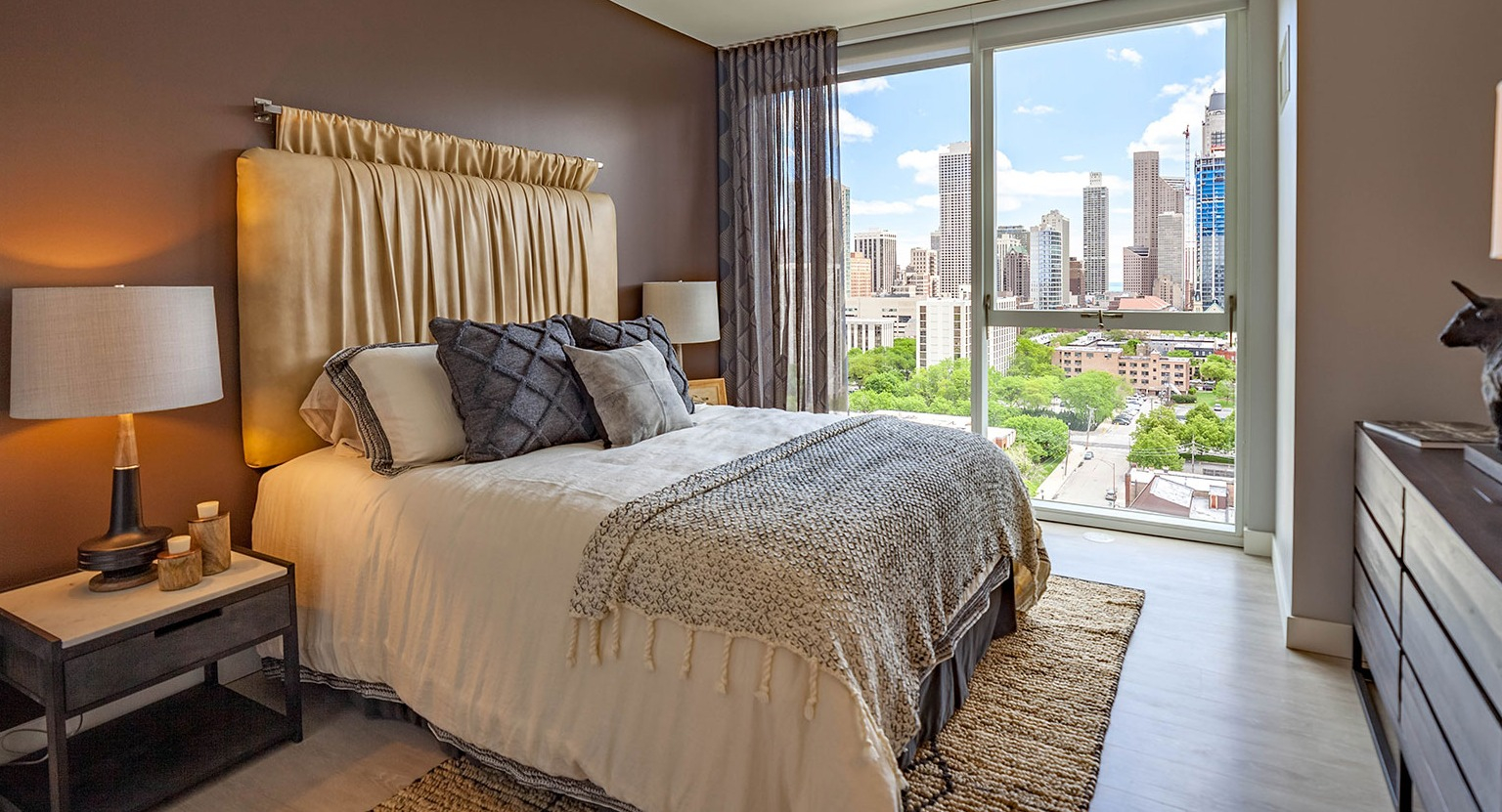 Luxurious bedroom at Niche 905 in Chicago, featuring a large bed, elegant decor, and stunning city views from floor-to-ceiling windows