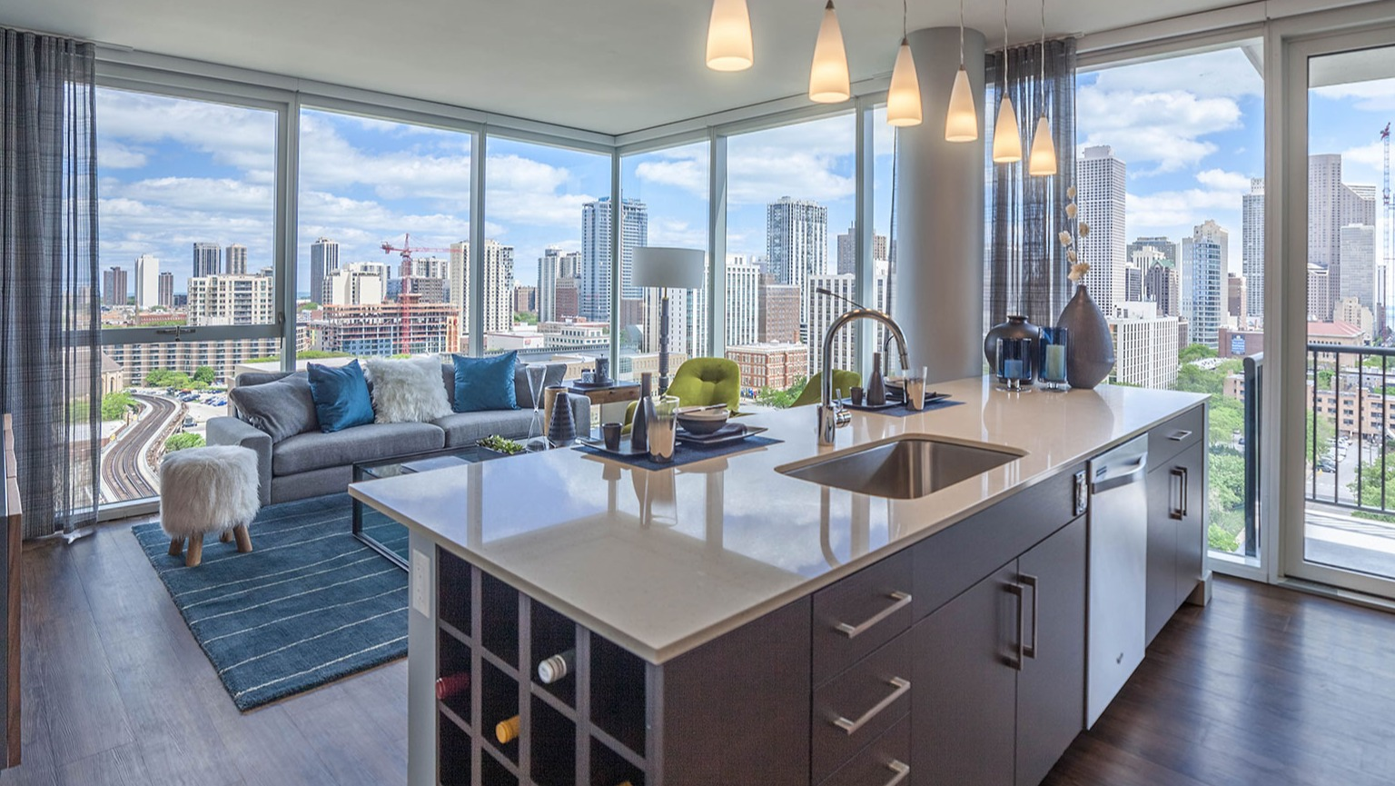 Bright apartment living room at Niche 905 in Chicago, featuring a modern kitchen island, comfortable sofa, and panoramic city views