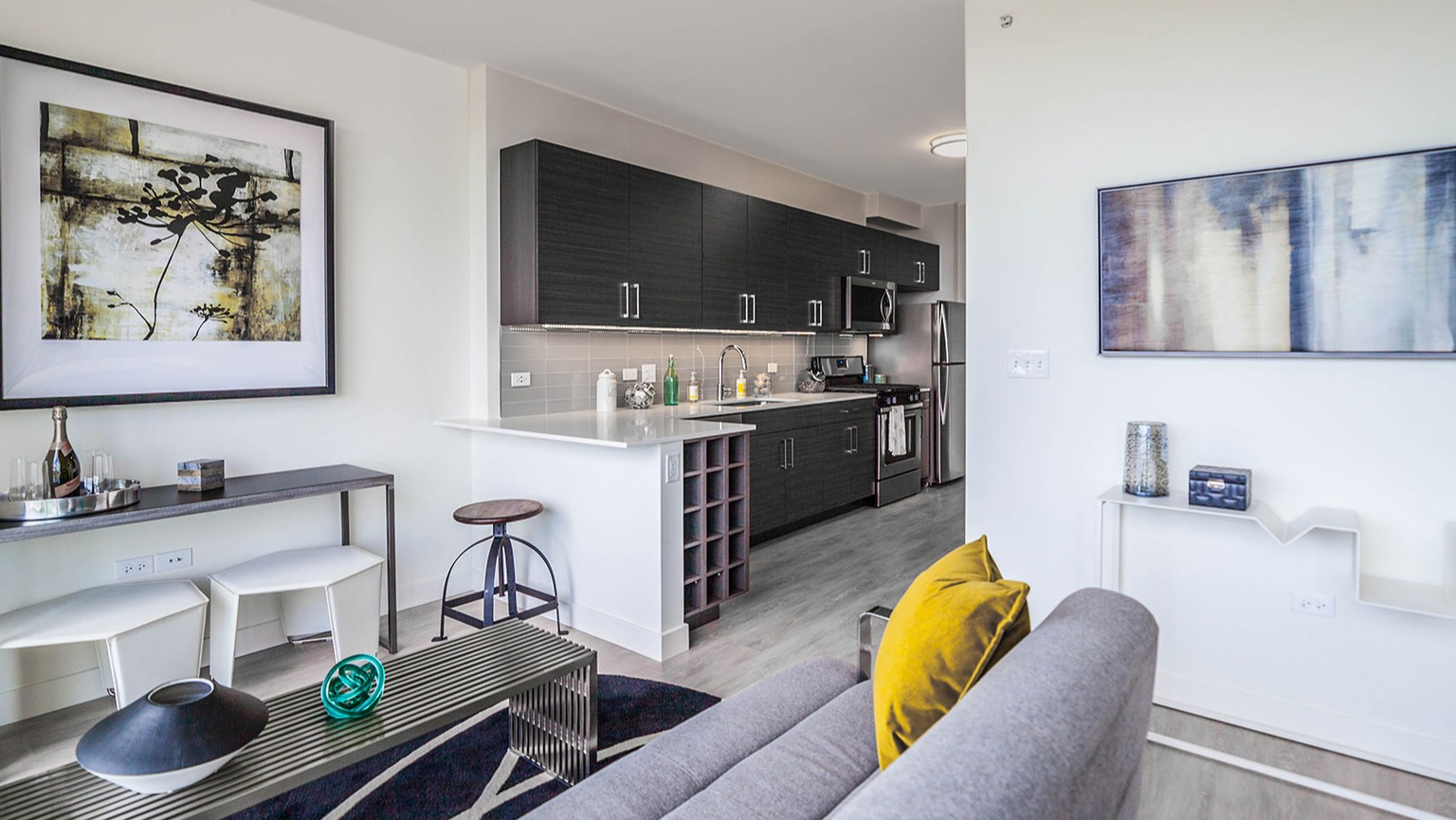 Contemporary living room and kitchenette at Niche 905 in Chicago, featuring a comfortable sofa, modern art, and sleek kitchen finishes