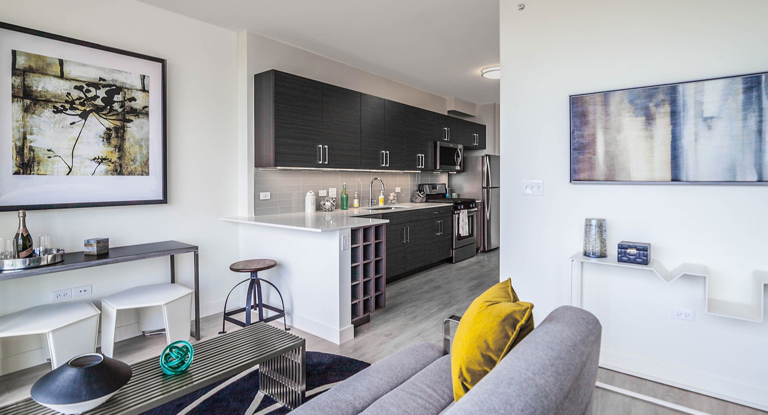 Contemporary living room and kitchenette at Niche 905 in Chicago, featuring a comfortable sofa, modern art, and sleek kitchen finishes