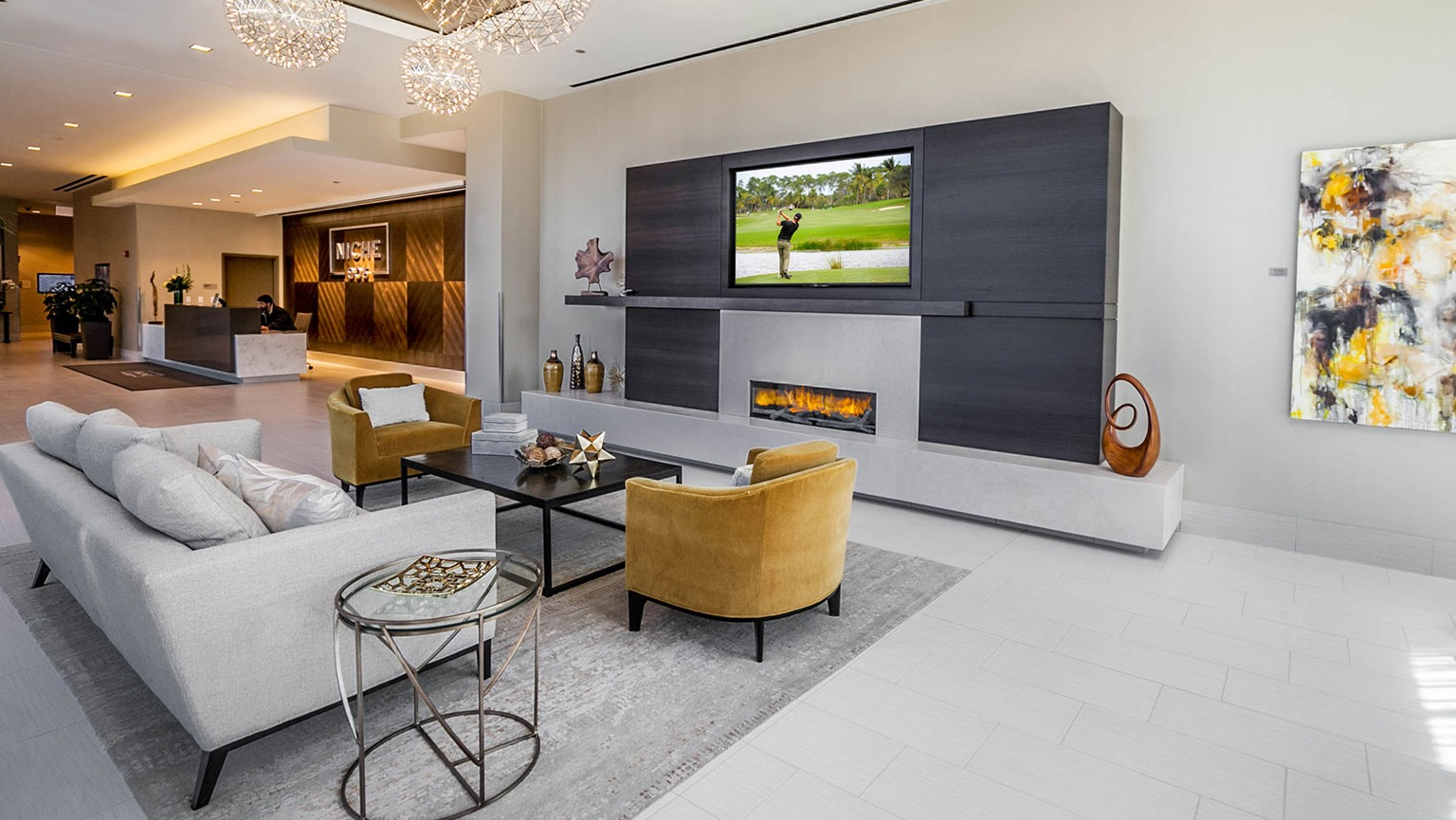 Luxurious lobby lounge at Niche 905 in Chicago, featuring modern chandeliers, a sleek fireplace with TV, and comfortable seating
