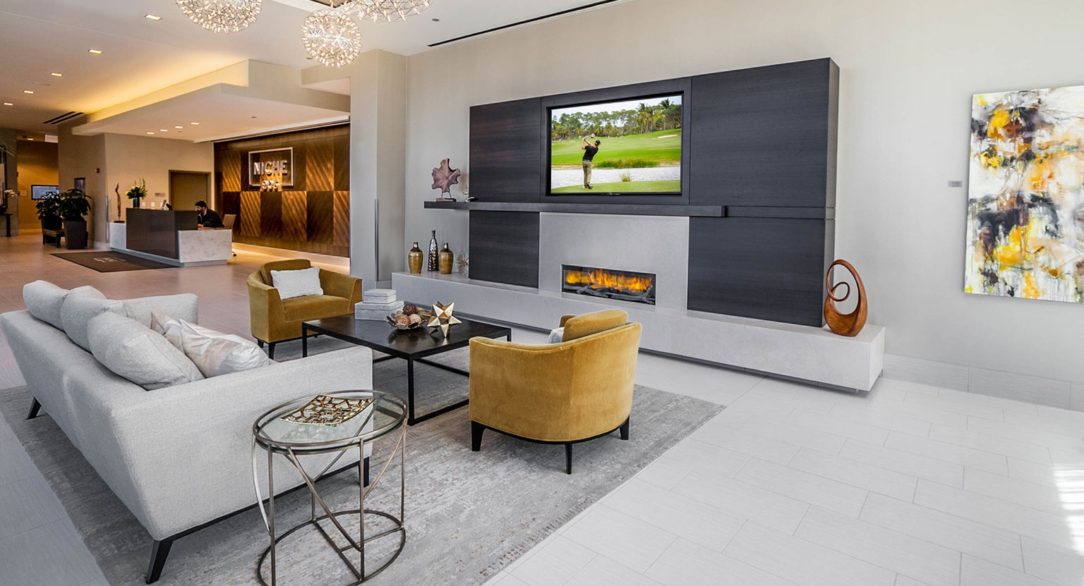 Luxurious lobby lounge at Niche 905 in Chicago, featuring modern chandeliers, a sleek fireplace with TV, and comfortable seating