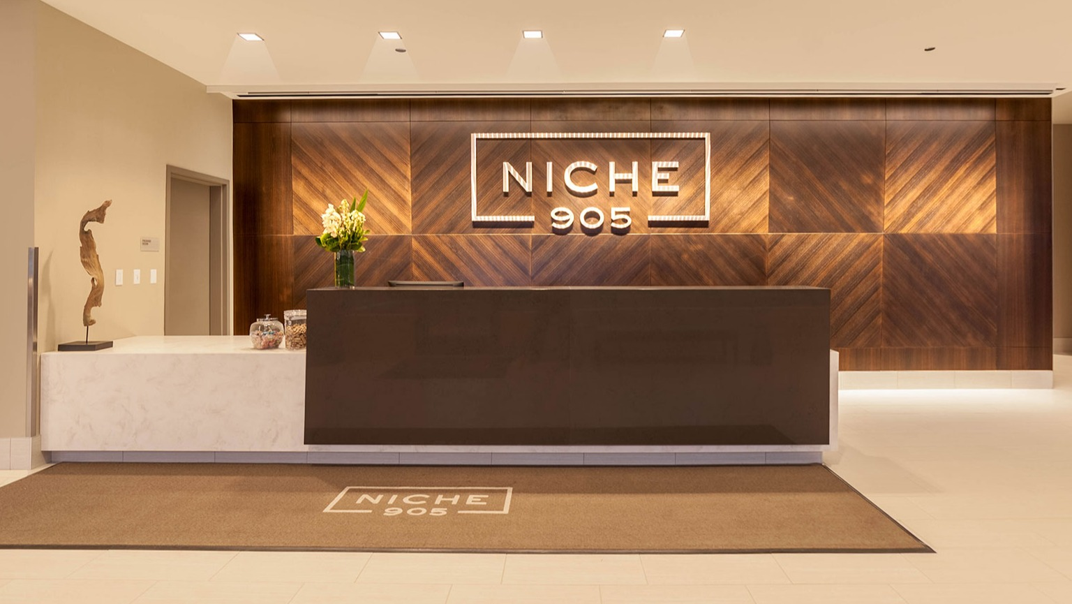 Grand lobby reception area at Niche 905 in Chicago, featuring a modern desk, elegant wood paneling, and clear branding