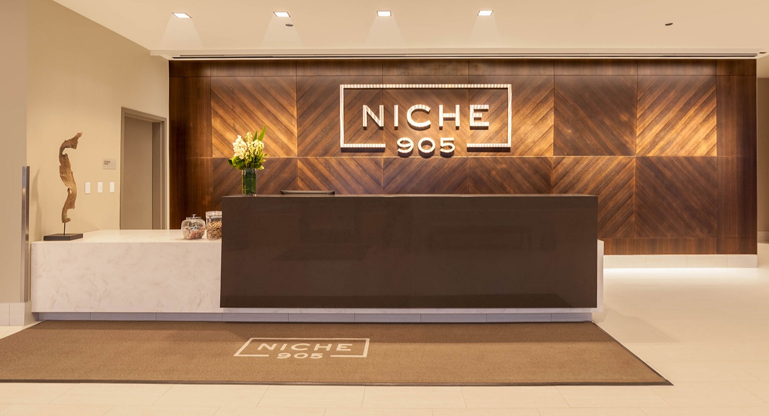 Grand lobby reception area at Niche 905 in Chicago, featuring a modern desk, elegant wood paneling, and clear branding