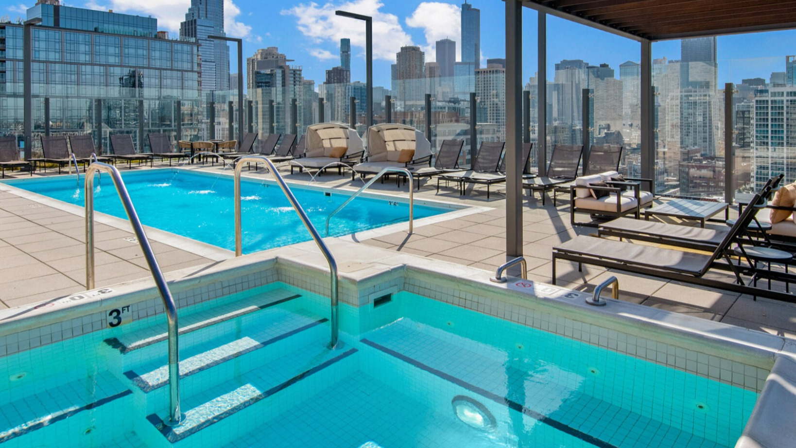 Sparkling rooftop pool and hot tub at Niche 905 in Chicago, surrounded by lounge chairs and offering breathtaking city skyline views