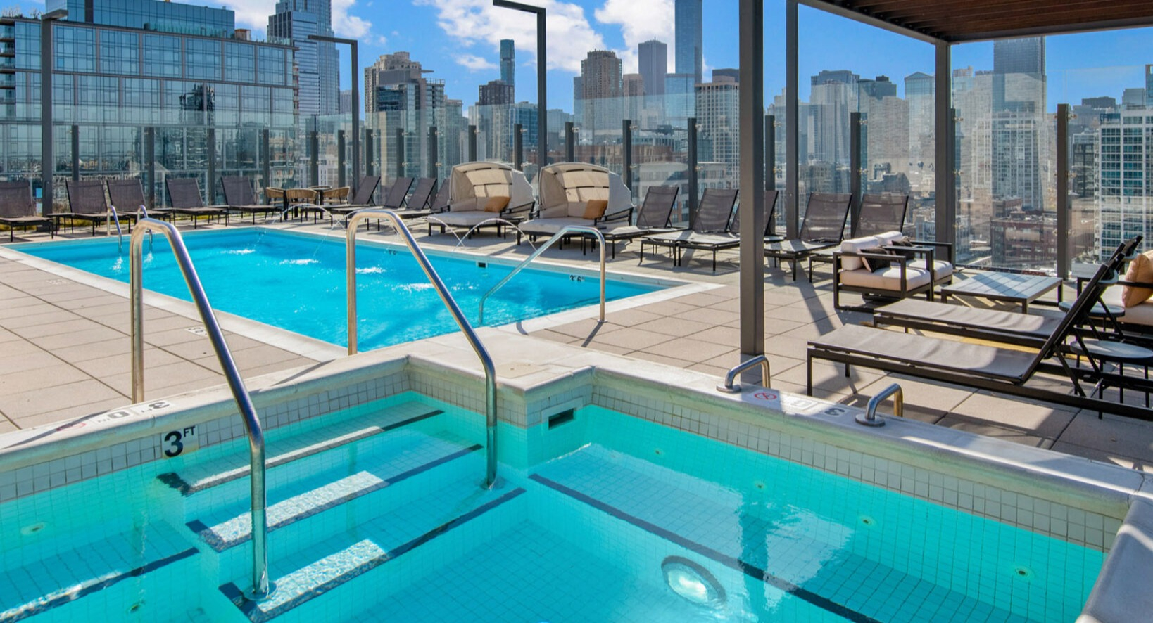 Sparkling rooftop pool and hot tub at Niche 905 in Chicago, surrounded by lounge chairs and offering breathtaking city skyline views