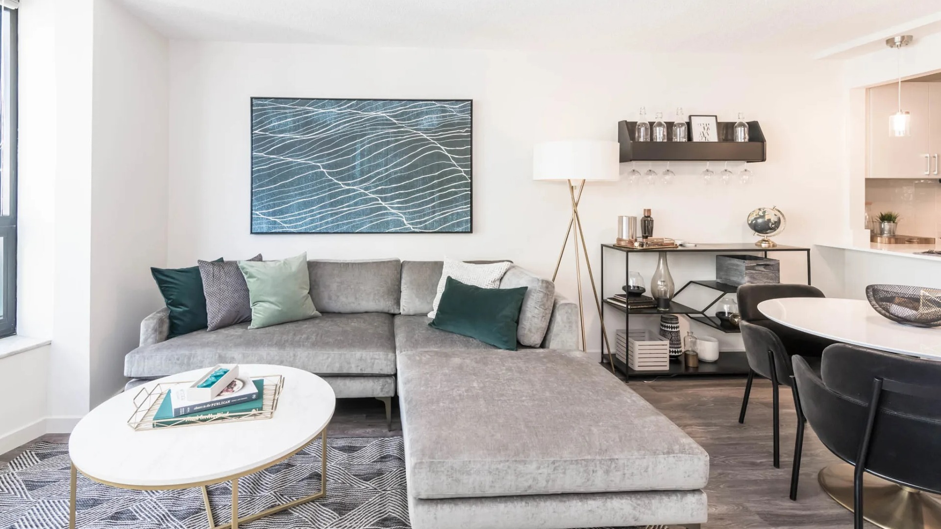 Bright living area at North Harbor Tower with sectional sofa, modern art, dining set, and bar shelf accents near the open kitchen in downtown Chicago