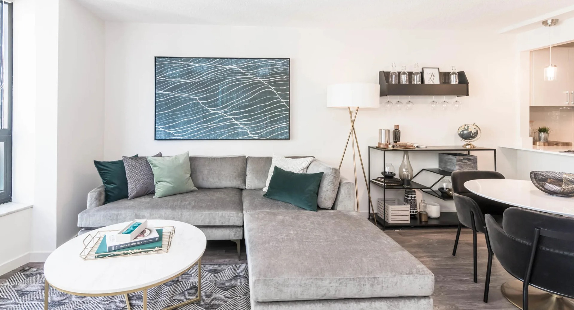 Bright living area at North Harbor Tower with sectional sofa, modern art, dining set, and bar shelf accents near the open kitchen in downtown Chicago