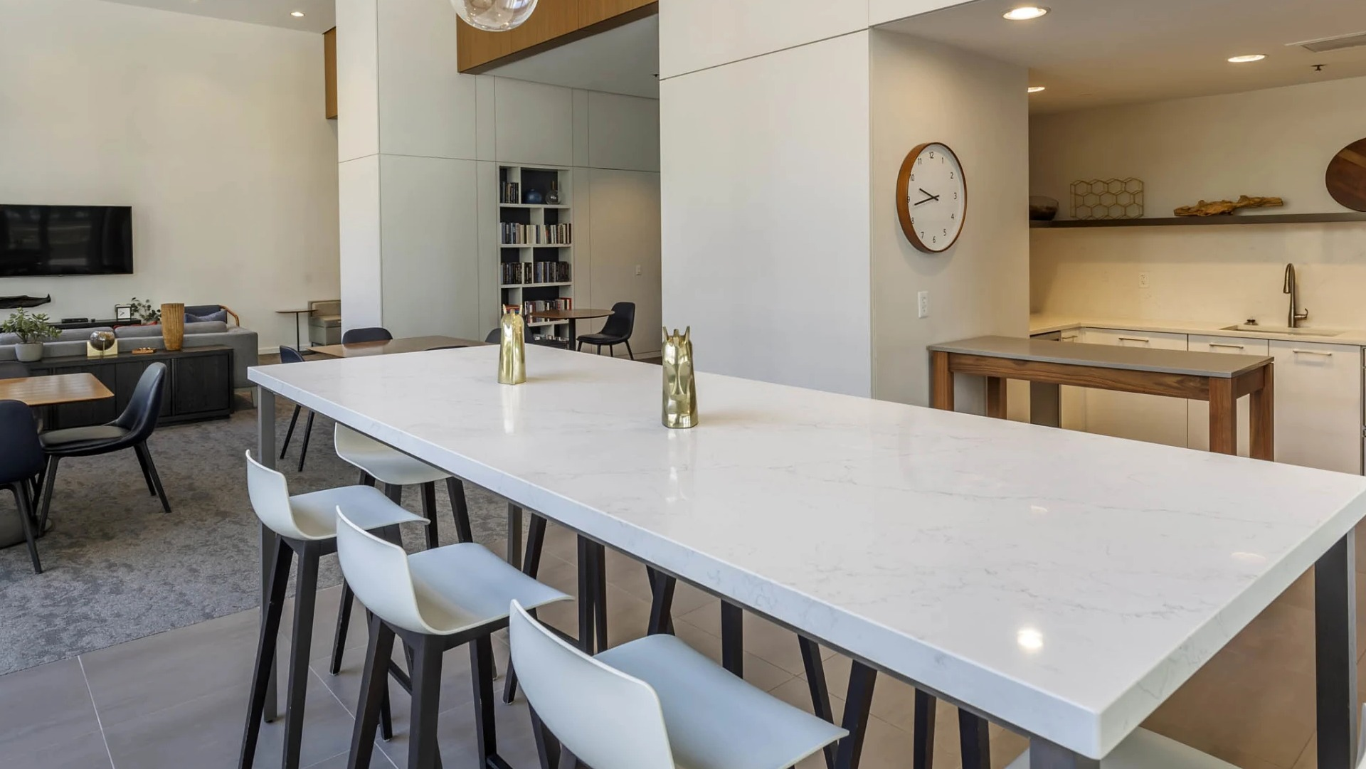 Bright community kitchen and clubroom at North Harbor Tower in Chicago, featuring a long quartz island with barstools, lounge seating, and media area for entertaining