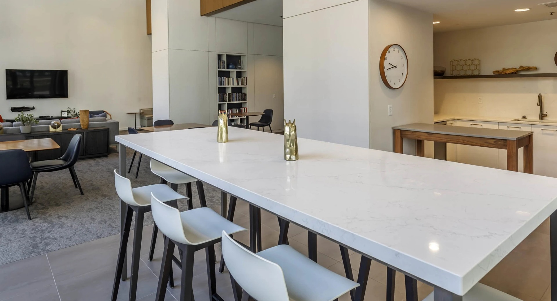 Bright community kitchen and clubroom at North Harbor Tower in Chicago, featuring a long quartz island with barstools, lounge seating, and media area for entertaining