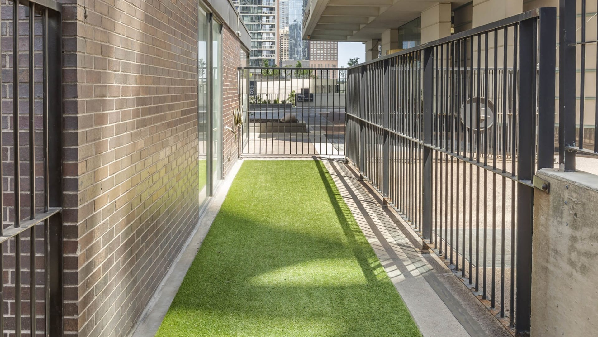 Outdoor dog run at North Harbor Tower in Chicago with artificial turf, fenced area, and city views designed for pet-friendly living