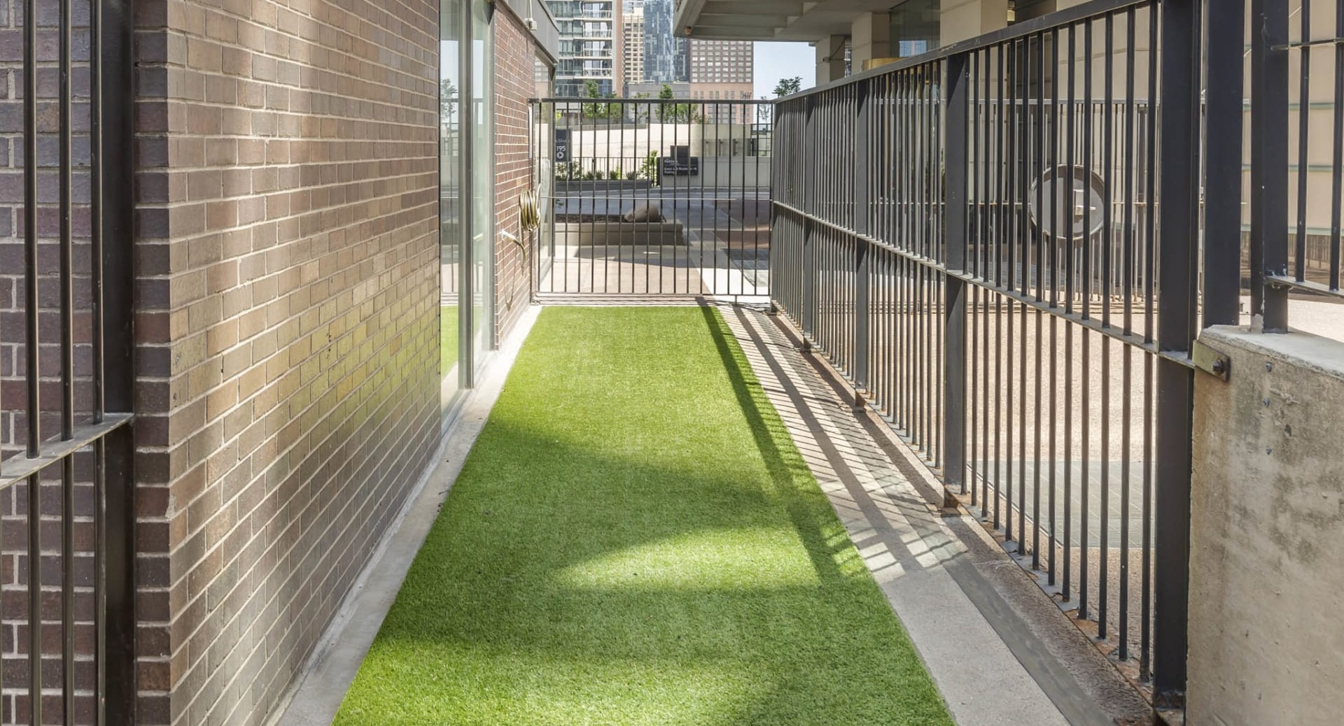 Outdoor dog run at North Harbor Tower in Chicago with artificial turf, fenced area, and city views designed for pet-friendly living