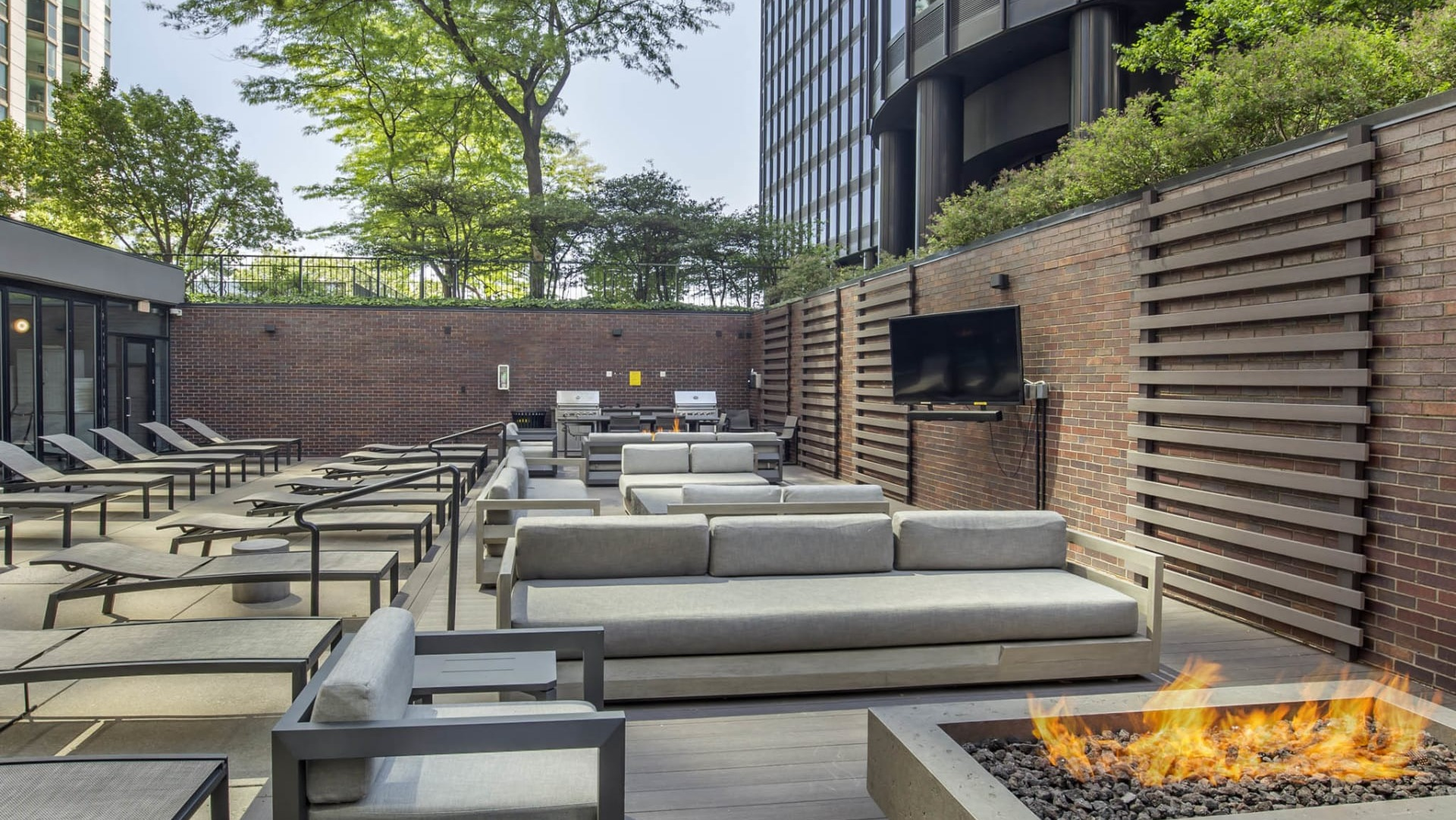 Stylish outdoor lounge at North Harbor Tower in Chicago with fire pit, cushioned seating, and a wall-mounted TV for entertaining