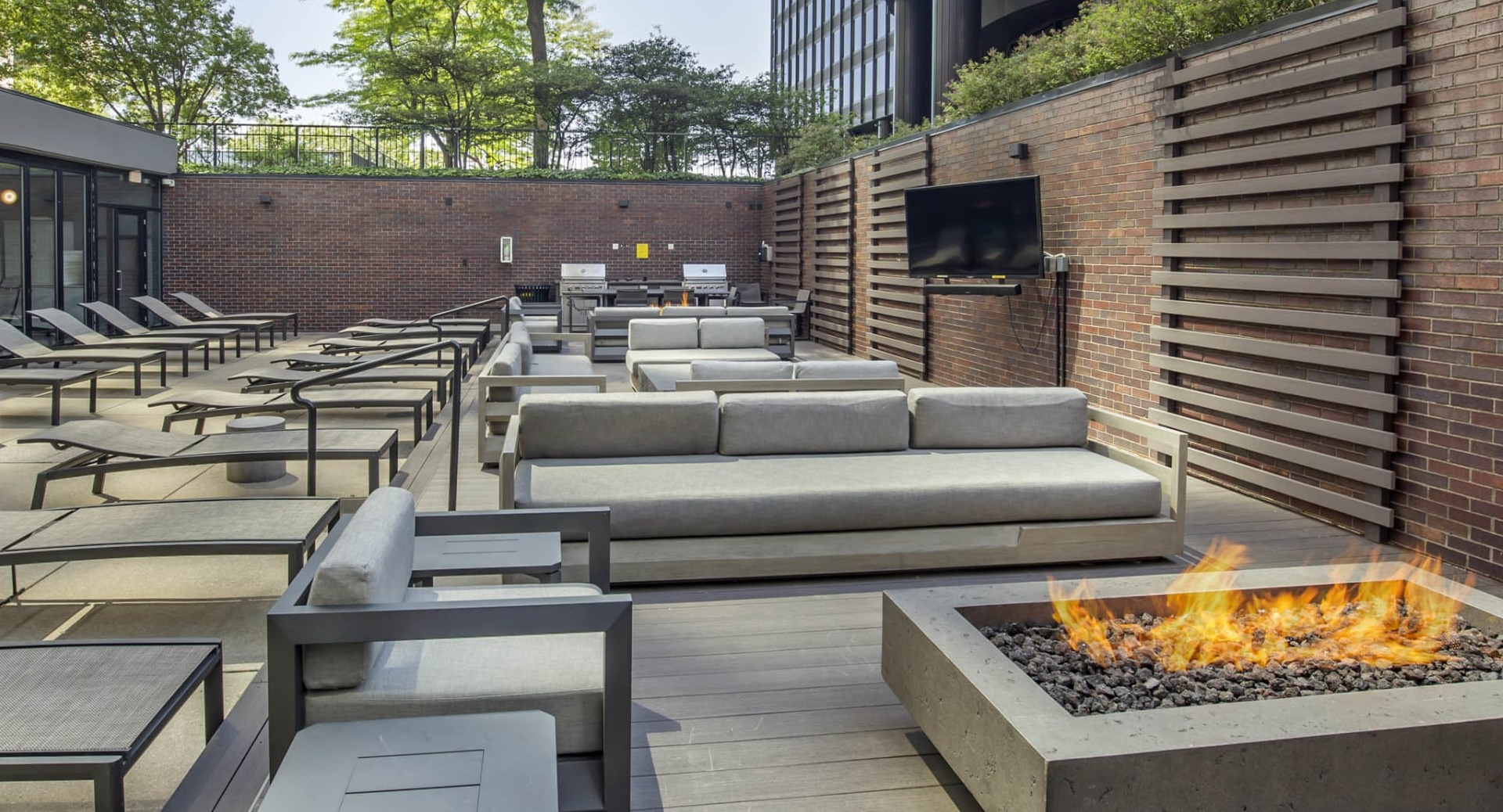Stylish outdoor lounge at North Harbor Tower in Chicago with fire pit, cushioned seating, and a wall-mounted TV for entertaining