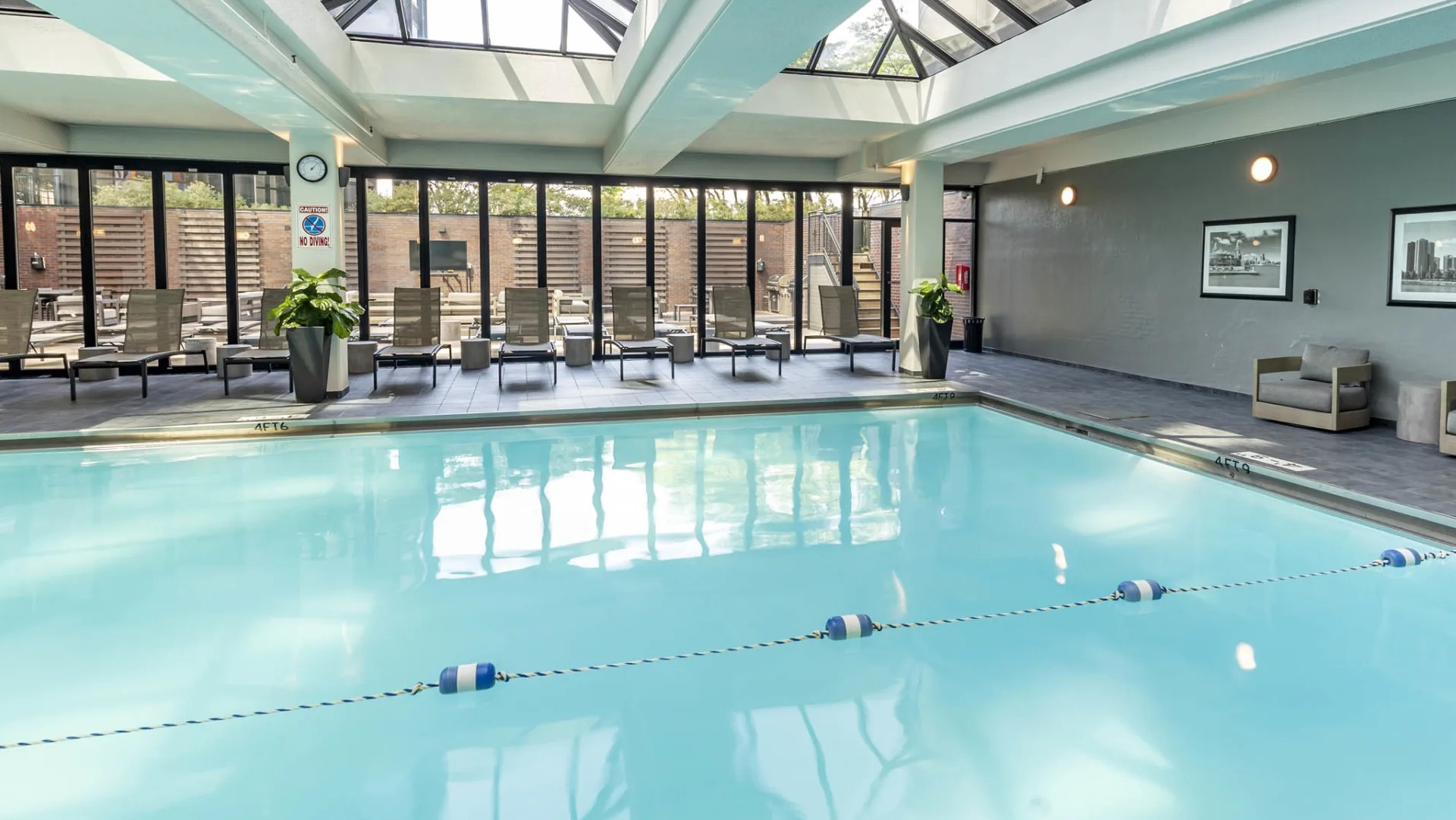 Spacious indoor pool at North Harbor Tower in Chicago with glass ceiling, lounge chairs, and access to the outdoor sundeck for year-round relaxation