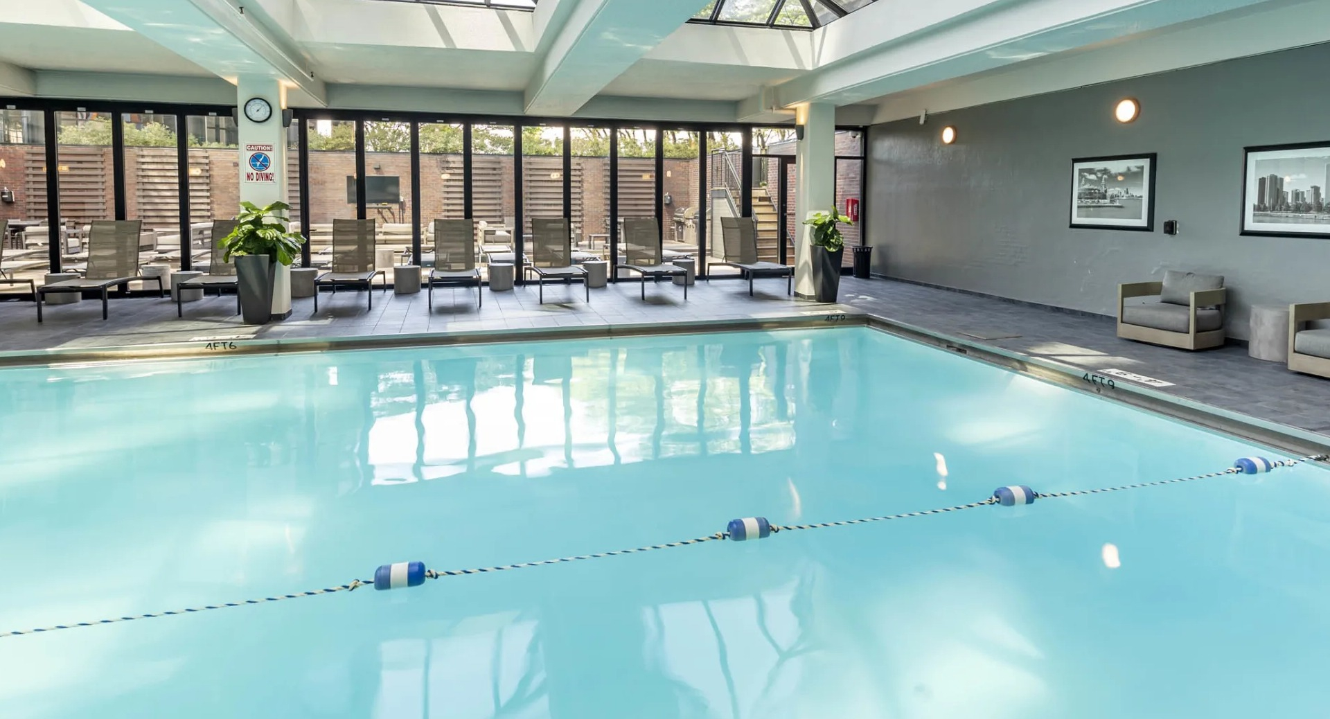 Spacious indoor pool at North Harbor Tower in Chicago with glass ceiling, lounge chairs, and access to the outdoor sundeck for year-round relaxation