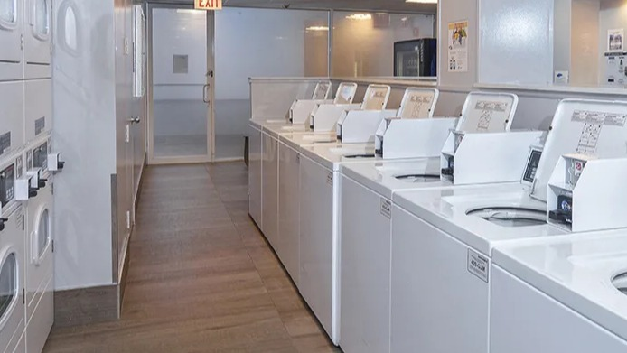 Laundry room at North Harbor Tower in Chicago with rows of washers and dryers, bright lighting, and spacious layout for resident convenience