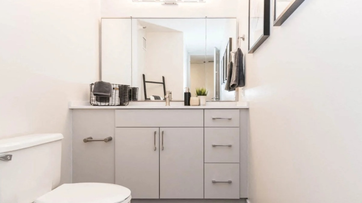Clean modern bathroom with a wide quartz-top vanity, large mirror, sleek lighting, and neutral finishes at North Harbor Tower apartments in Chicago
