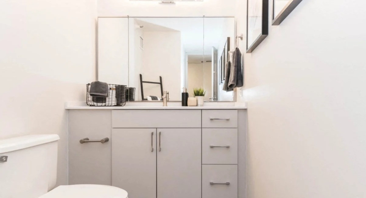Clean modern bathroom with a wide quartz-top vanity, large mirror, sleek lighting, and neutral finishes at North Harbor Tower apartments in Chicago