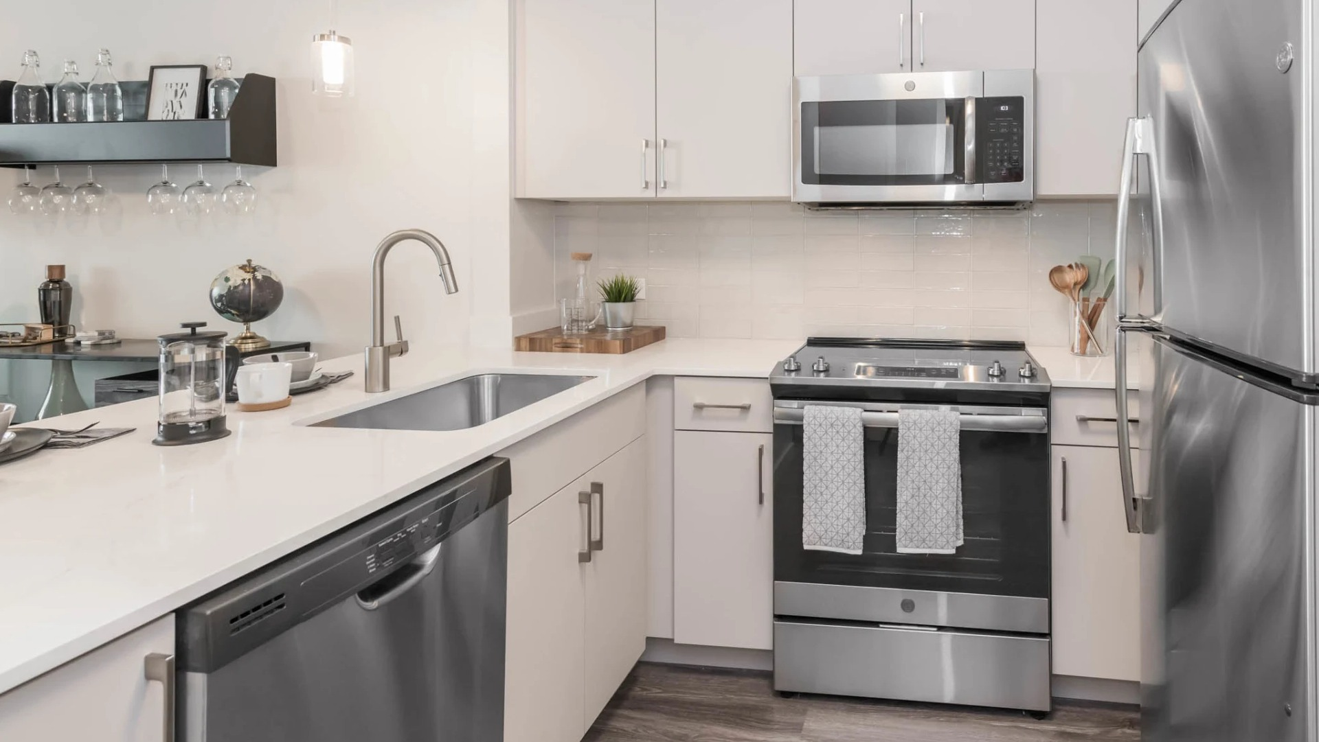 Modern kitchen with white cabinetry, quartz counters, stainless steel appliances, gas range, dishwasher, and a pass-through bar at North Harbor Tower in Chicago