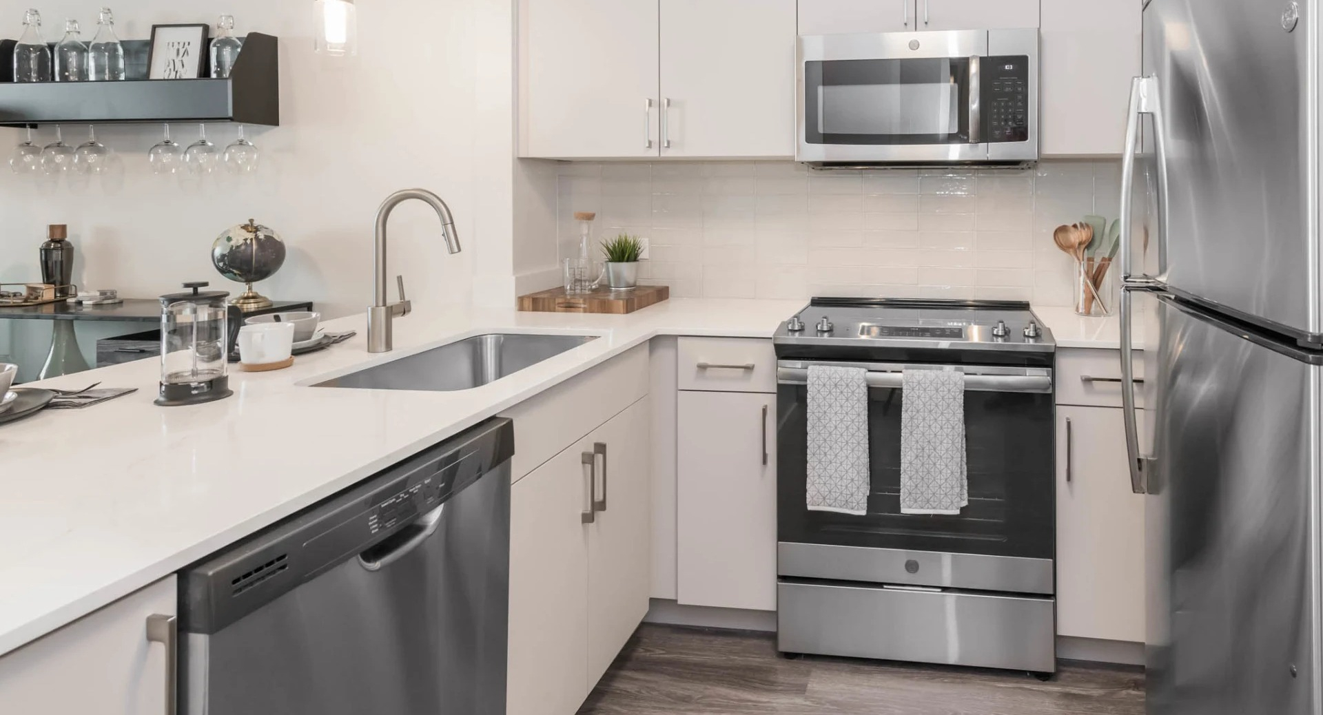 Modern kitchen with white cabinetry, quartz counters, stainless steel appliances, gas range, dishwasher, and a pass-through bar at North Harbor Tower in Chicago