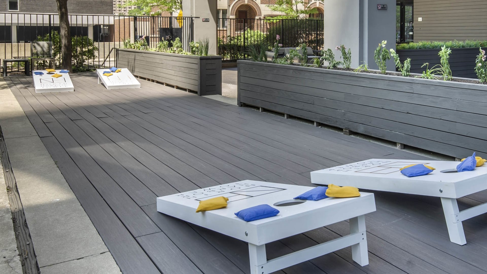 Outdoor games and entertainment space at North Harbor Tower in Chicago with cornhole boards, seating areas, and planters for a fun community vibe
