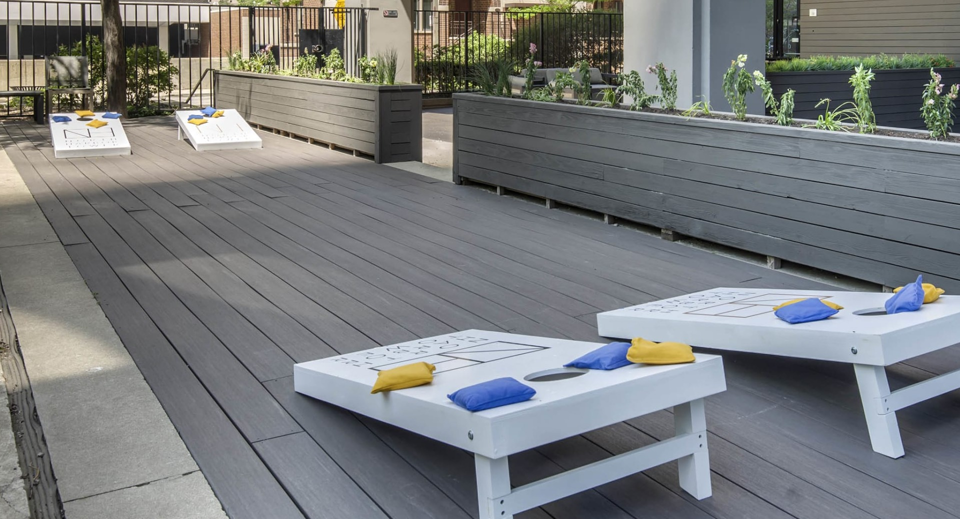 Outdoor games and entertainment space at North Harbor Tower in Chicago with cornhole boards, seating areas, and planters for a fun community vibe