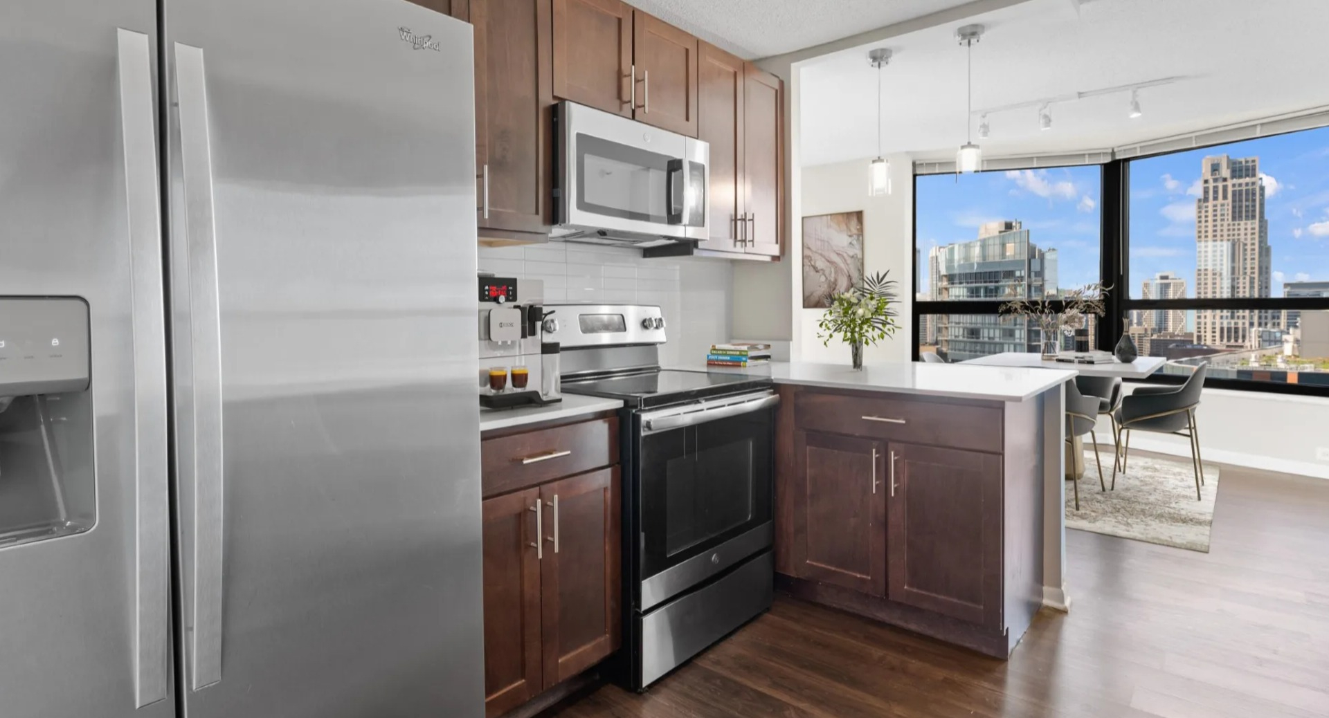 Open studio at North Harbor Tower combining a cozy bed, chic sofa, dining nook, and large windows showcasing downtown Chicago cityscape views