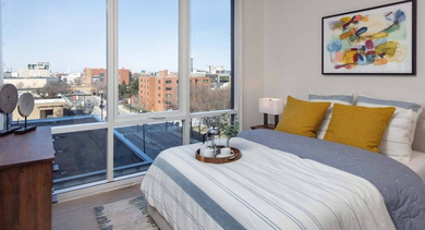 Bright bedroom with a comfortable bed, colorful accents, and large windows offering urban views at North+Vine in Chicago