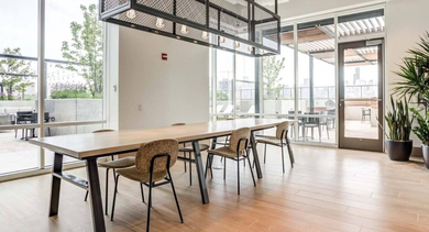 Bright and modern co-working space with a large communal table, comfortable chairs, and outdoor access at North+Vine in Chicago