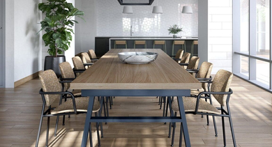 Elegant communal dining room with a long table, contemporary chairs, and a kitchen area in the background at North+Vine in Chicago