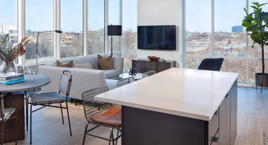 Open-concept kitchen and living area with a large island, dining table, and floor-to-ceiling windows offering corner city views at North+Vine in Chicago