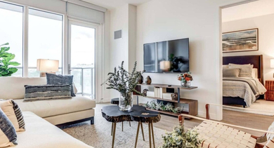 Bright living room with comfortable seating, modern decor, a balcony, and a glimpse into a stylish bedroom at North+Vine in Chicago