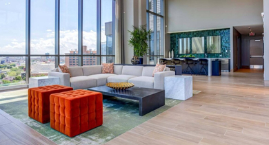 Spacious entertainment lounge with a large sectional sofa, vibrant seating, and big windows looking out onto the city at North+Vine in Chicago