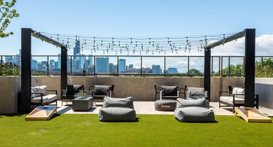Sunny rooftop turf area with outdoor seating, bean bags, cornhole, and city skyline views at North+Vine in Chicago