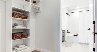 Spacious walk-in closet with shelving and baskets, leading into a modern bathroom at North+Vine apartments in Chicago