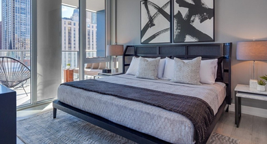 Chic bedroom with a comfortable bed, modern art, and direct access to a private balcony with city views at OLD TOWN PARK ONE in Chicago