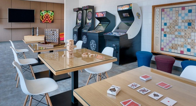 Vibrant game room with arcade machines, board games, comfortable seating, and neon wall art at OLD TOWN PARK ONE in Chicago