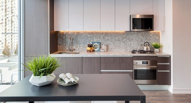 Sleek kitchen and dining area with modern appliances, two-tone cabinetry, and a dining table by a large window at OLD TOWN PARK ONE in Chicago