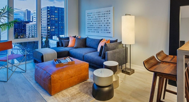 Contemporary living room with a large sectional sofa, leather ottoman, and floor-to-ceiling windows offering city views at OLD TOWN PARK ONE in Chicago