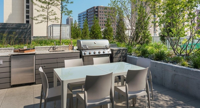 Outdoor grilling station with a large barbecue, dining table, and lush greenery, ideal for al fresco meals at OLD TOWN PARK ONE in Chicago