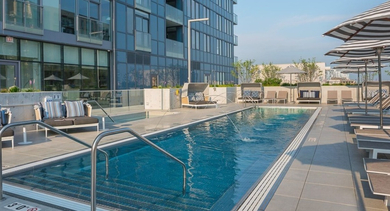 Luxurious swimming pool area with comfortable lounge chairs and striped umbrellas, perfect for sunbathing at OLD TOWN PARK ONE in Chicago