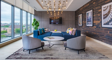 Chic resident lounge with a large blue sectional, modern decor, wood paneling, and a TV viewing area at OLD TOWN PARK ONE in Chicago