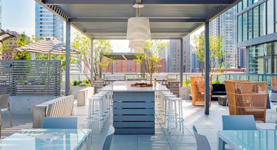 Stylish rooftop dining area under a modern pergola, featuring long tables and bar seating for entertaining at OLD TOWN PARK ONE in Chicago
