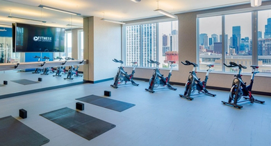 Bright spin and yoga studio with exercise bikes, yoga mats, and city views through large windows at OLD TOWN PARK ONE in Chicago